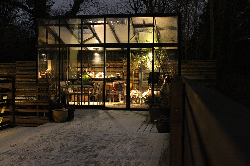 Glass lean to greenhouse with interior lights on a dark evening in Boulder, Colorado with secure locking mechanism aluminum hardware South Table Sheds