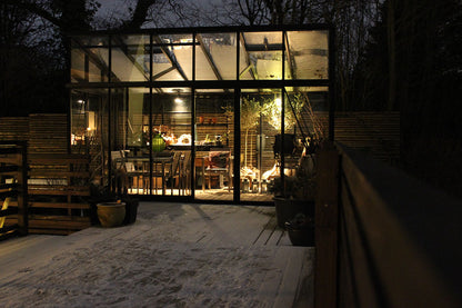 Glass lean to greenhouse with interior lights on a dark evening in Boulder, Colorado with secure locking mechanism aluminum hardware South Table Sheds