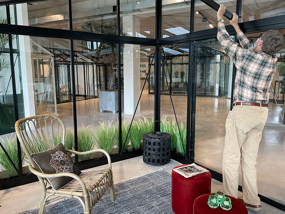 Man adjusting a large glass panel in a modern interior setting